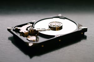 Open hard drive showing internal metal parts and disk.