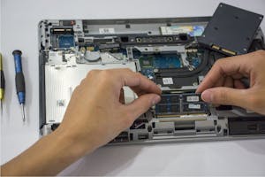Technician working on internal components inside a laptop.